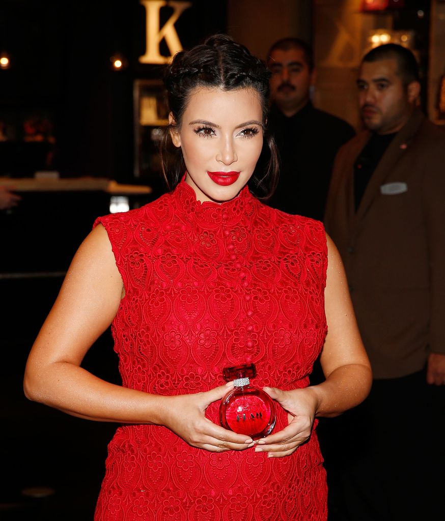 Kim Kardashian in a red holding a red perfume in 2013