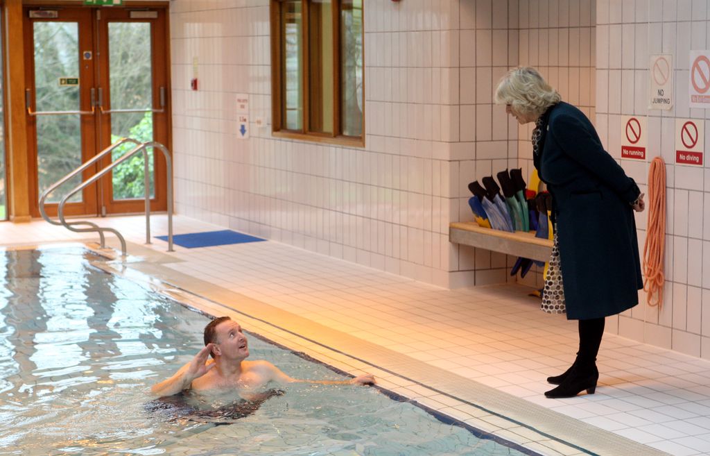 Queen Consort Camilla talking to a man in a swimming pool