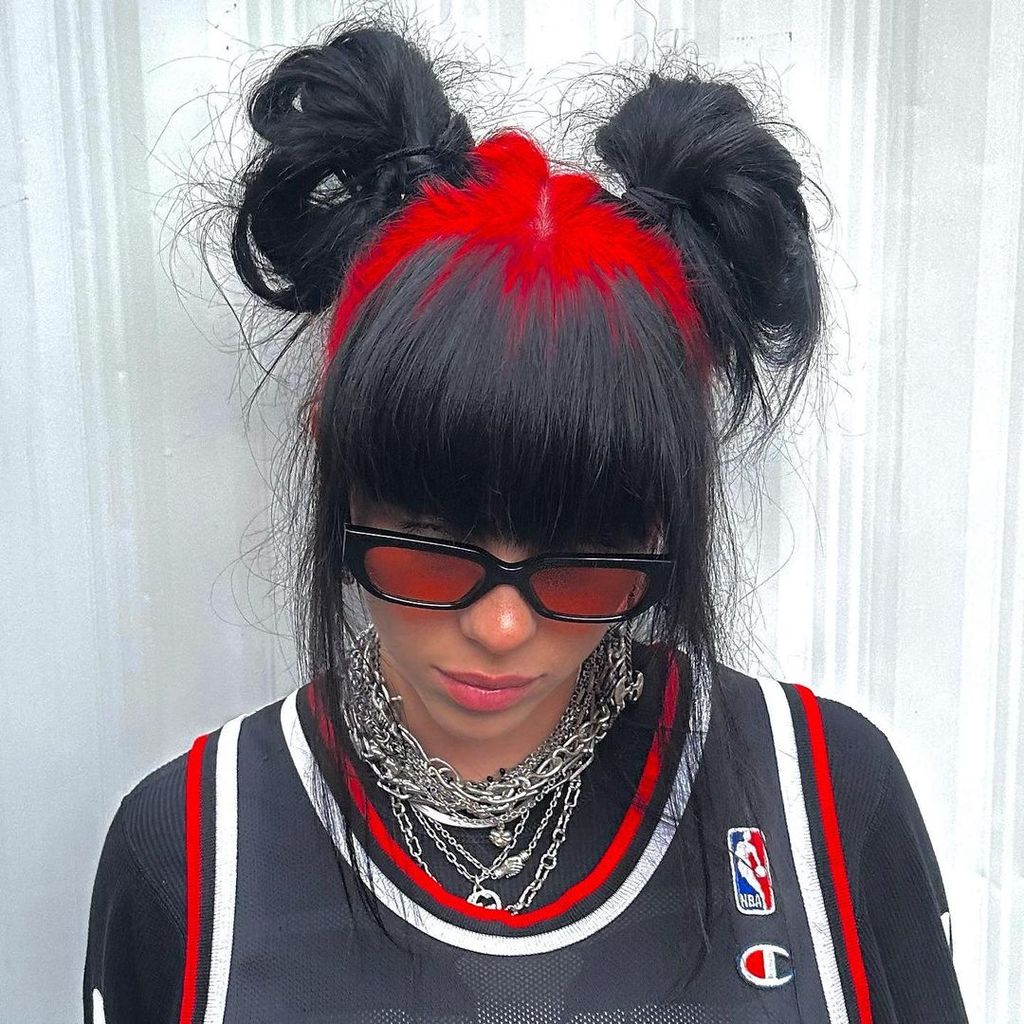 Billie Eilish with red and black hair in space buns