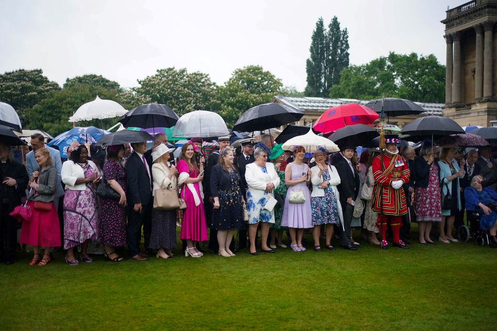 Guests attend under their umbrellas The Sovereign's Garden Party  at Buckingham Palace