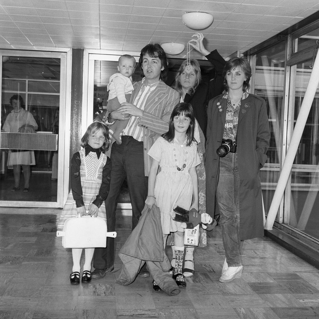 Black and white photograph of man and woman in airport with three children and a teenager