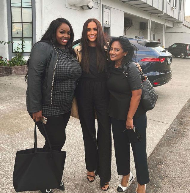 meghan markle poses in an all black outfit with two women