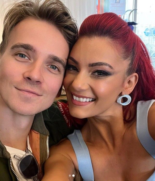 Dianne Buswell and Joe Sugg smiling with their heads close together behind the scenes of Strictly