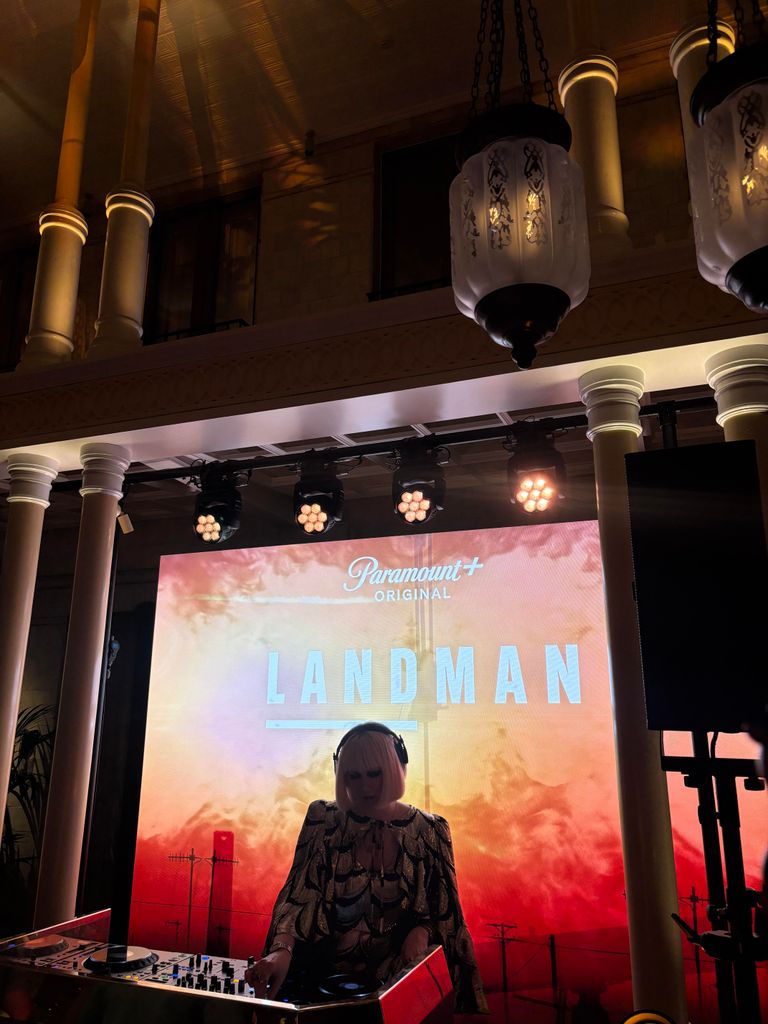 The DJ at the afterparty in front of the Landman sign