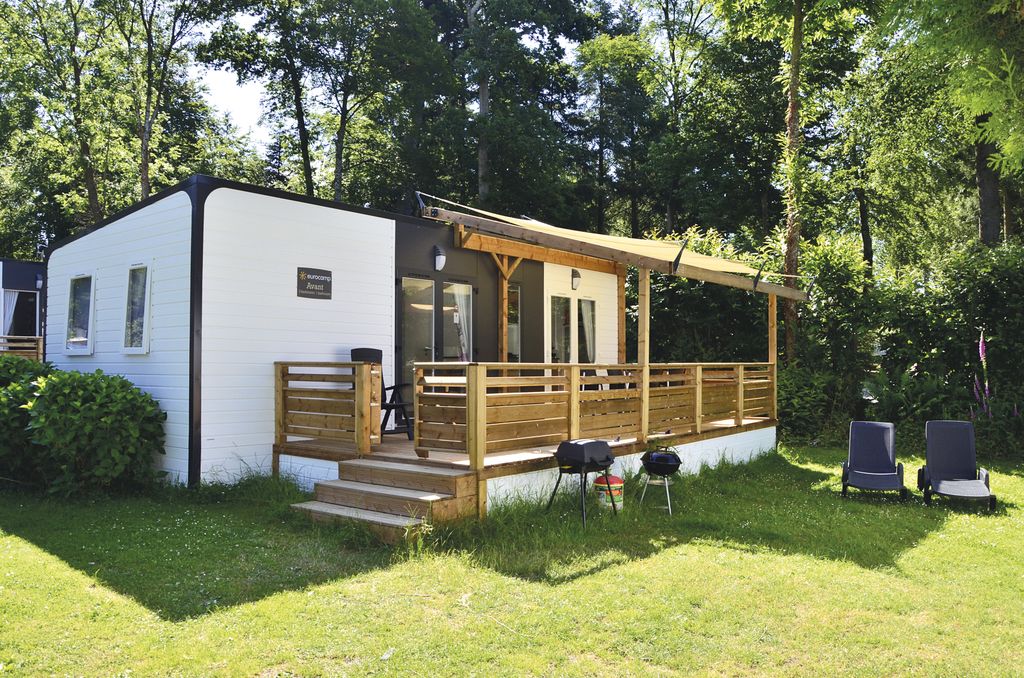 Chalet with decking on lawn with trees in the background