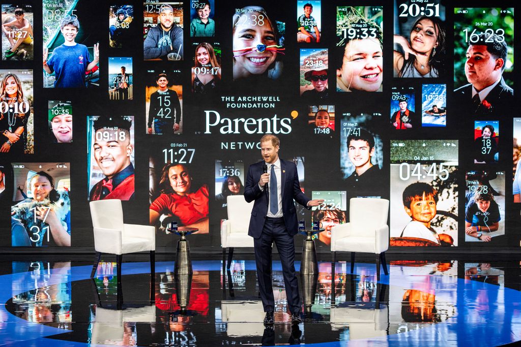 Prince Harry on stage in front of images of phone lockscreens