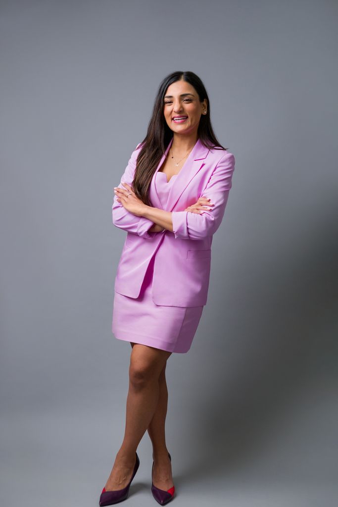woman in lilac skirt suit with her arms crossed smiling 