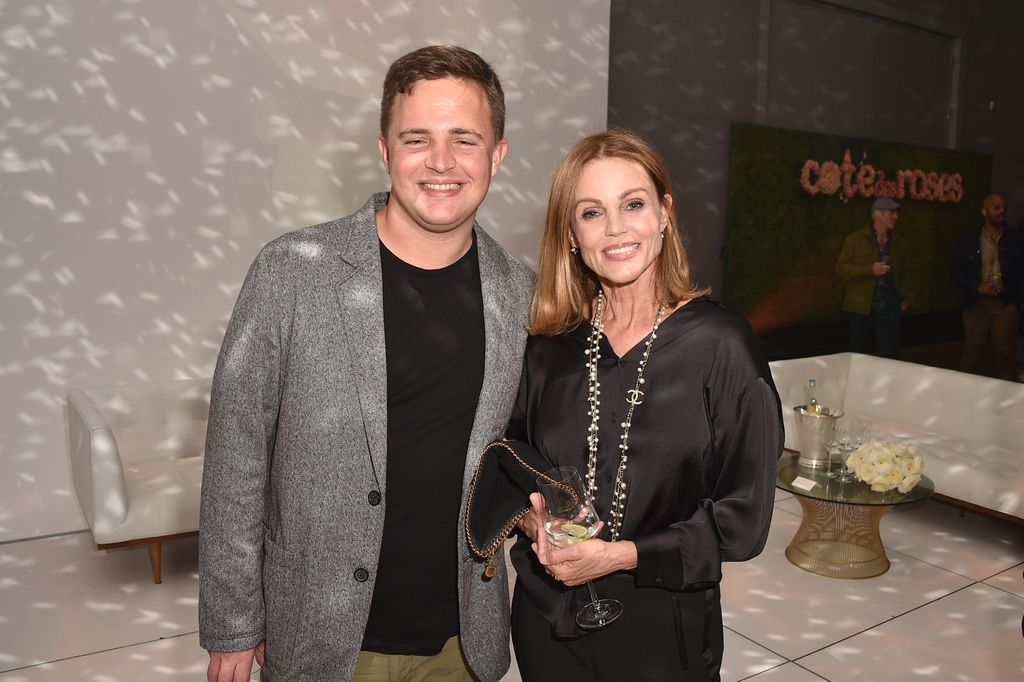 James Mason se tient à côté de sa mère Belinda dans une veste grise et un t-shirt noir. 