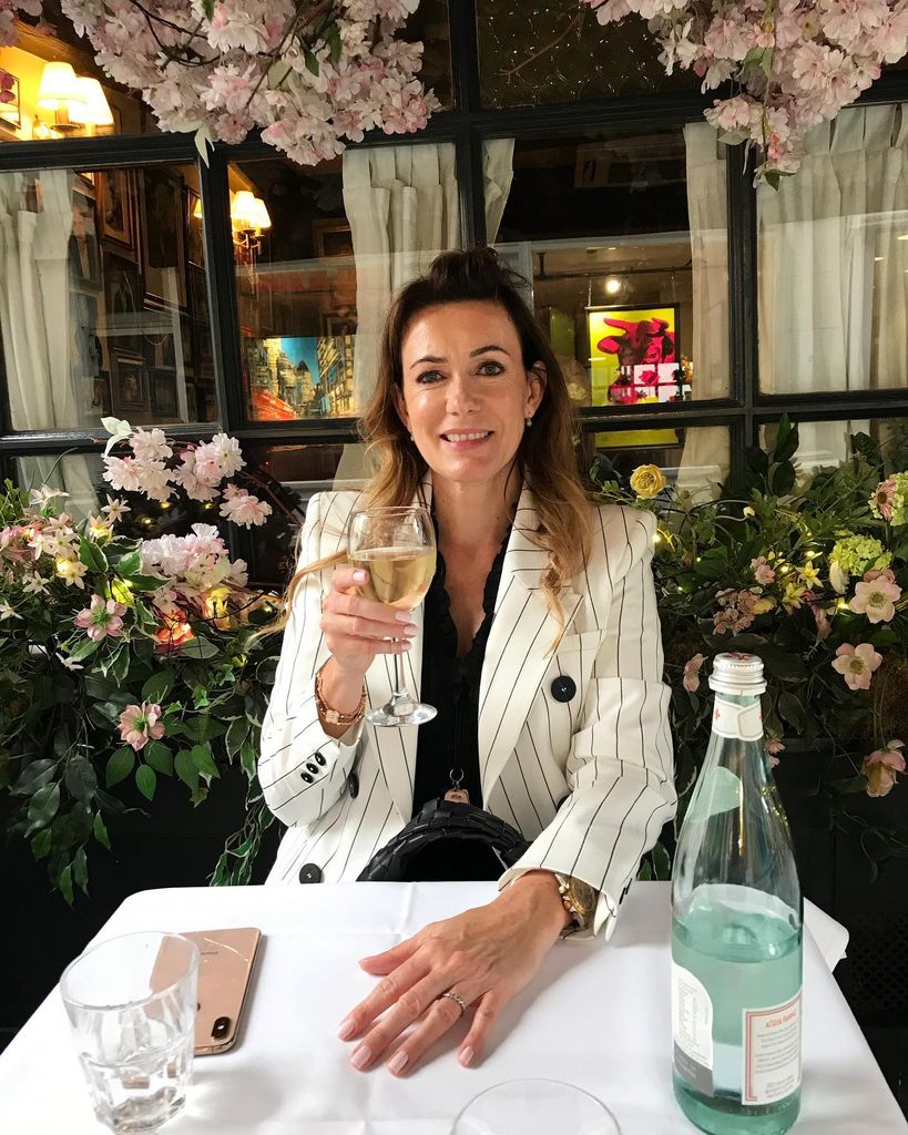 Anna Richards sat posing with a glas of wine in a restaurant