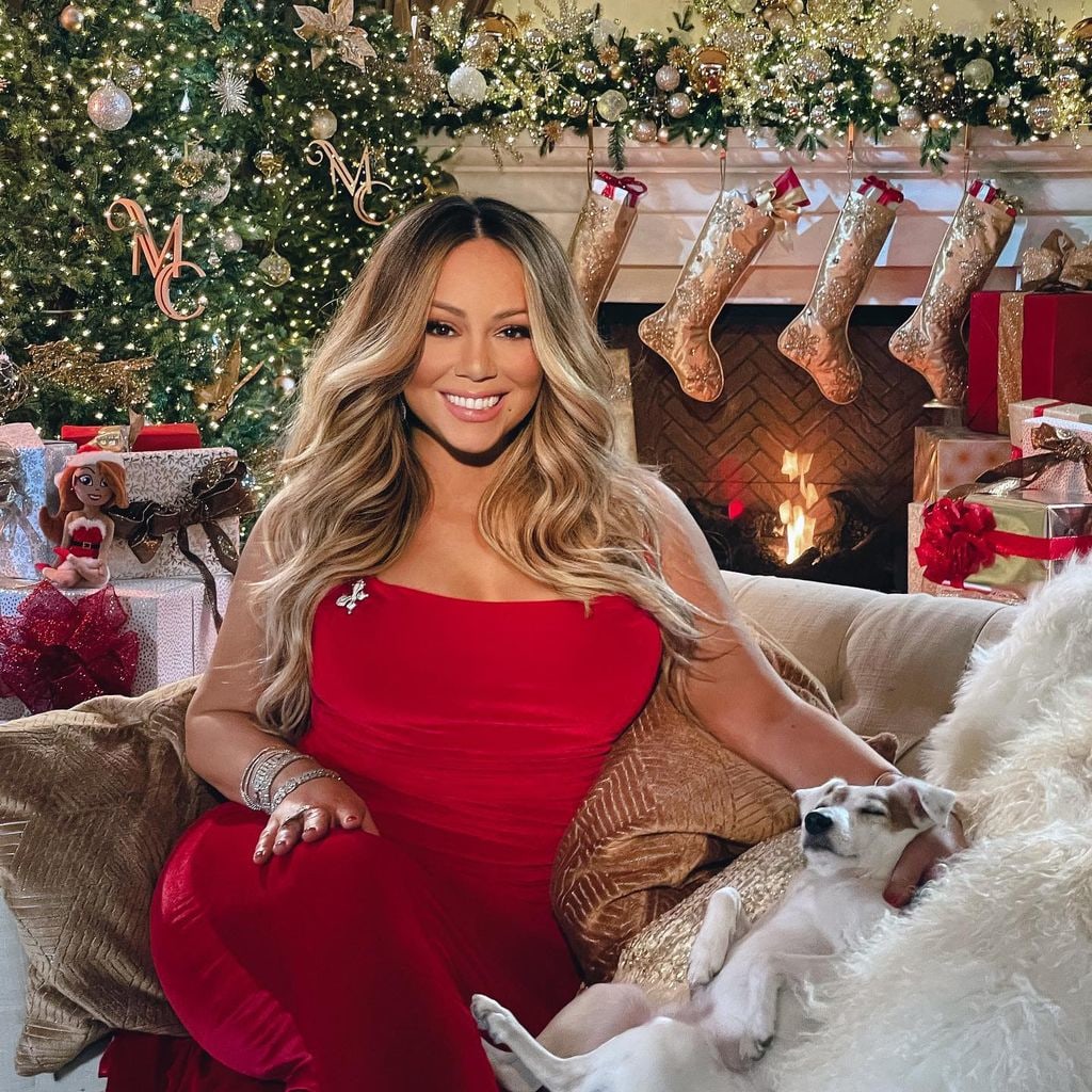 Mariah Carey sitting with her dog by the fireplace at her home. 