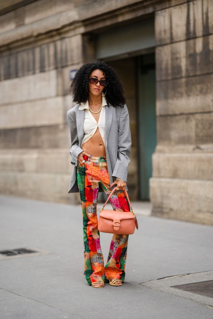  woman wearing sunglasses, gray blazer and orange Coach bag