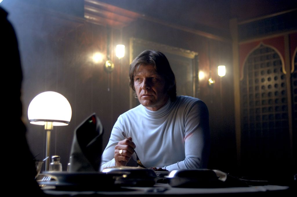man in white roll neck sitting at desk in dark room