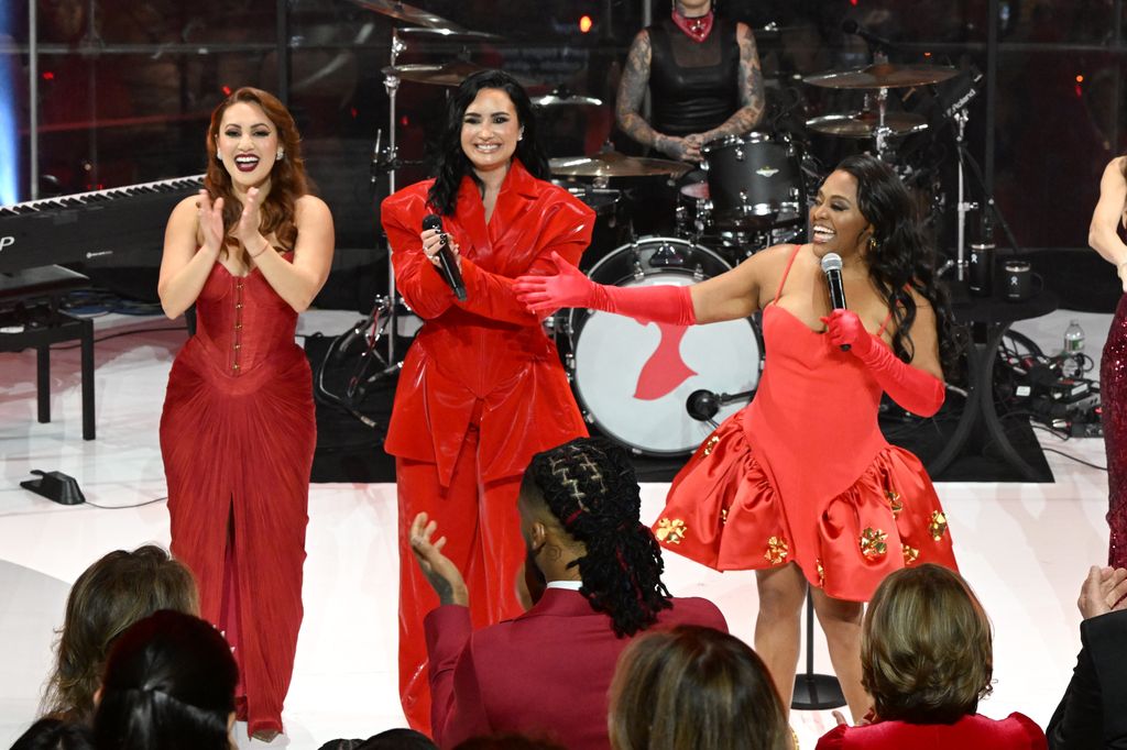 Francia Raisa, Demi Lovato, and Sherri Shepherd posing on the runway during The American Heart Association's Red Dress Collection Concert 