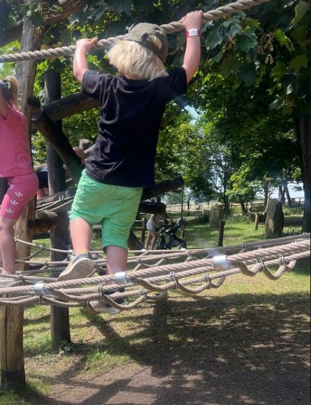 little boy in green shorts on a climbing frame 