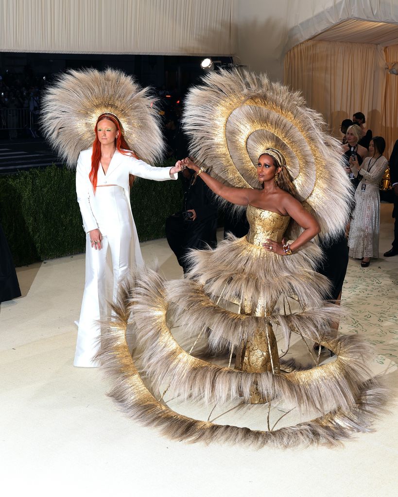 Harris Reed in white suit and feathered headpiece and Iman in feathered tiered gown and headpiece 