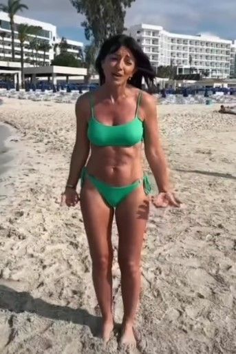 davina mccall wearing green bikini showcasing abs on beach