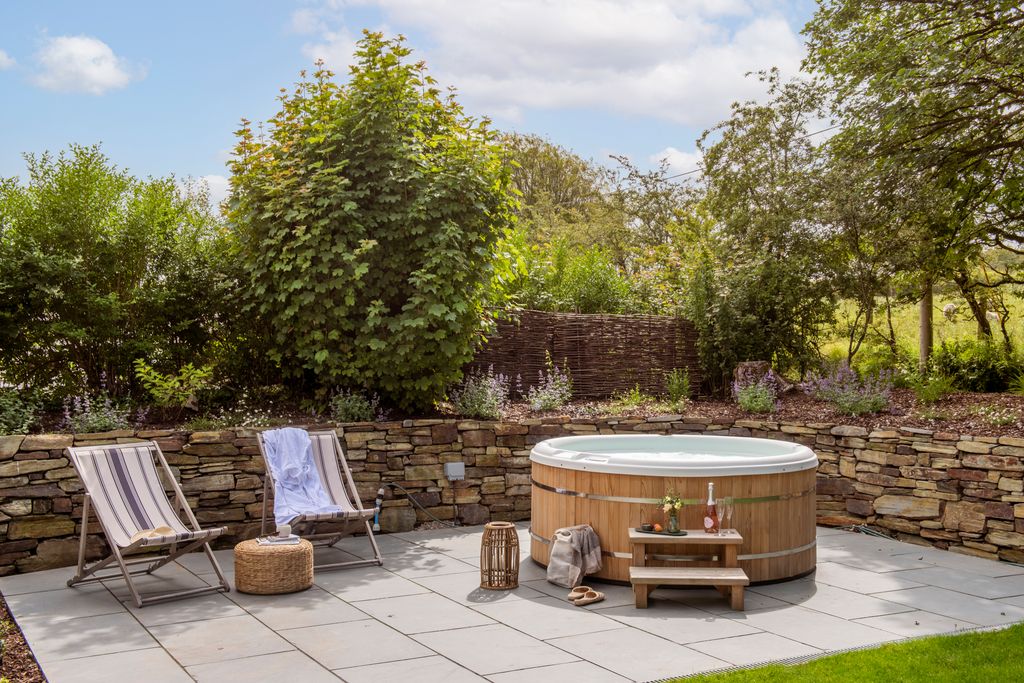 The hot tub at Moss Farmhouse is pictured with two deckchairs