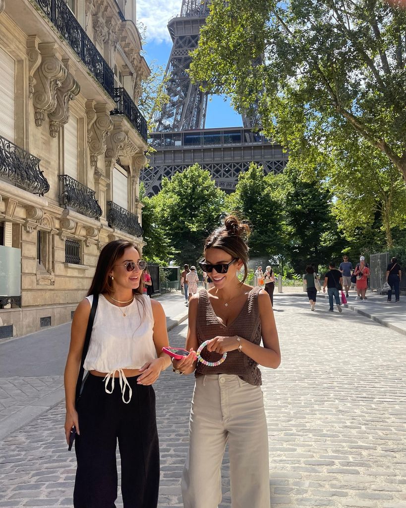 two women walking in front of eiffel tower