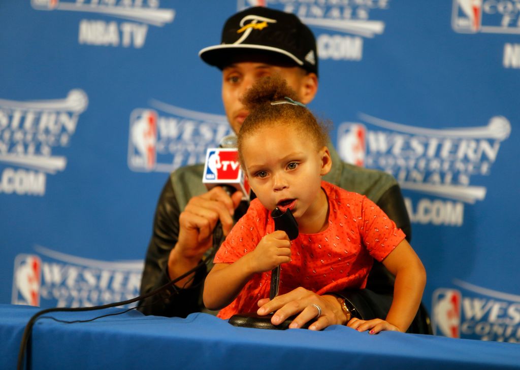 Golden State Warriors' Stephen Curry speaks to the media as his daughter Riley plays after Warriors' 104-90 win over Houston Rockets in Game 5 of NBA Playoffs' Western Conference Finals at Oracle Arena in Oakland, Calif., on Wednesday, May 27, 2015
