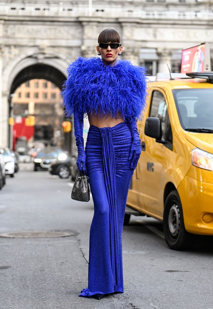 Katya Tolstava looks with a dress and gloves of Banco Blue Bronx and Banco, Jimmy Choo Silver Bon Bag, Stuart Weitzman Shoes and Pianegonda pending with black sunglasses outside the Bronx and Bank Show during NYFW F/W 2025 on February 05, 2025 in New York York City