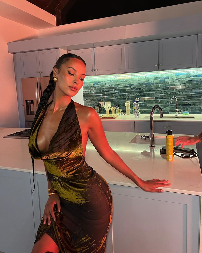A photo of Maya Jama leaning on a kitchen table 