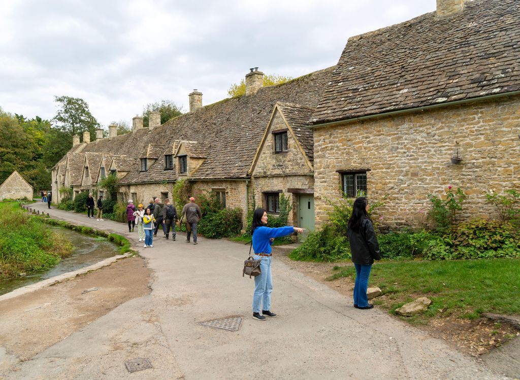 Tourists visiting famous Cotswold buildings at Arlington Row, Bibury, Gloucestershire, England, UK