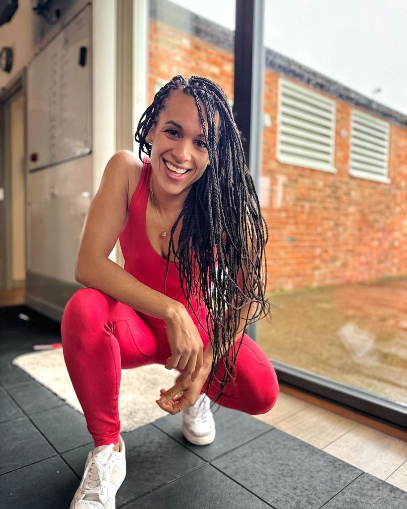 woman with red activewear smilng in a lunge