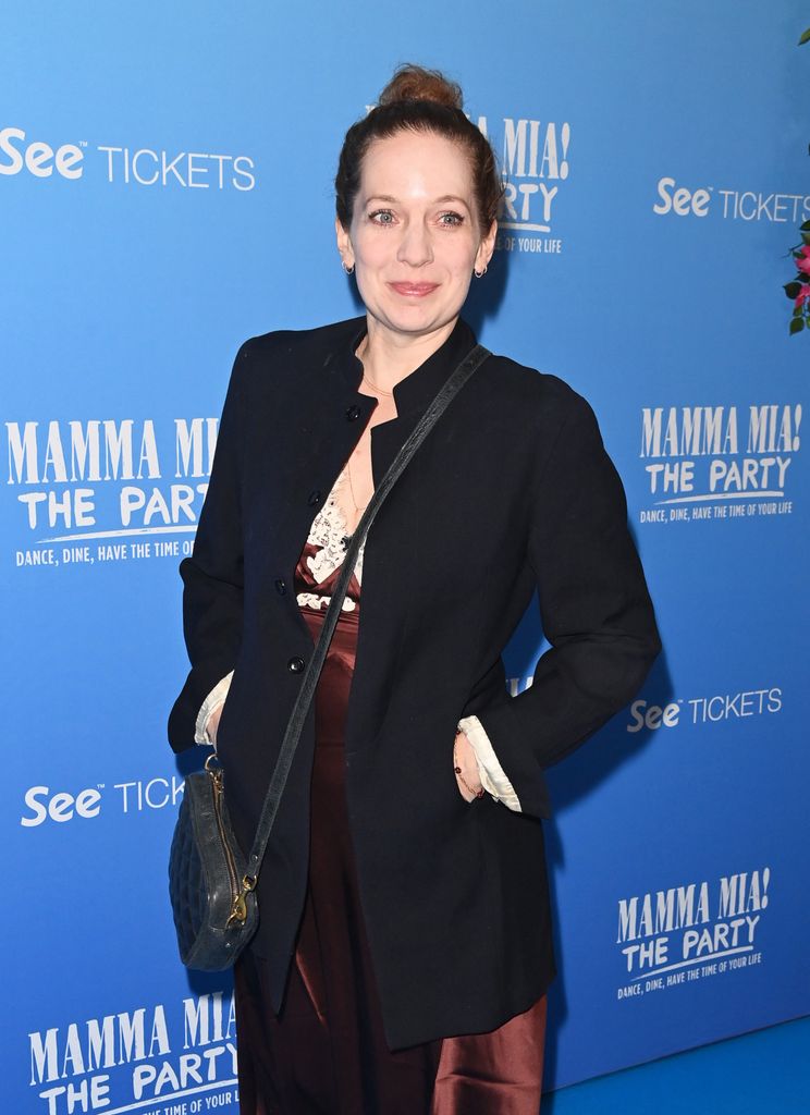 Katherien Parkinson in a black outfit in front of a blue background