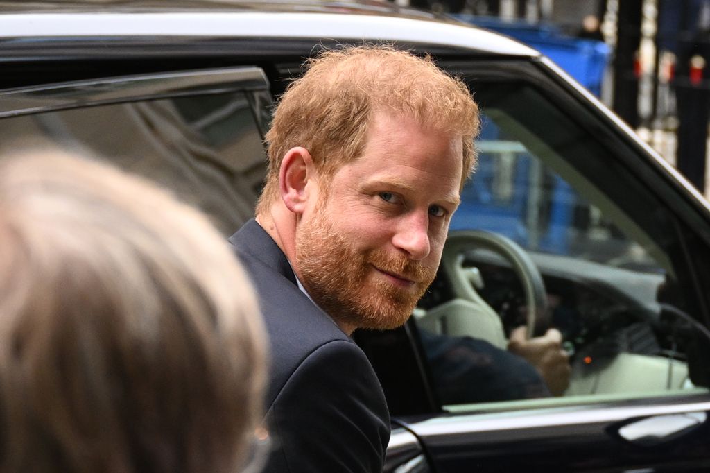 Prince Harry smiles at photographers as he arrives at the High Court