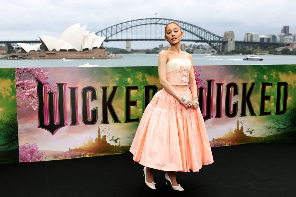 Ariana Grande poses by Sydney Harbour Bridge in pink skirt and crop top