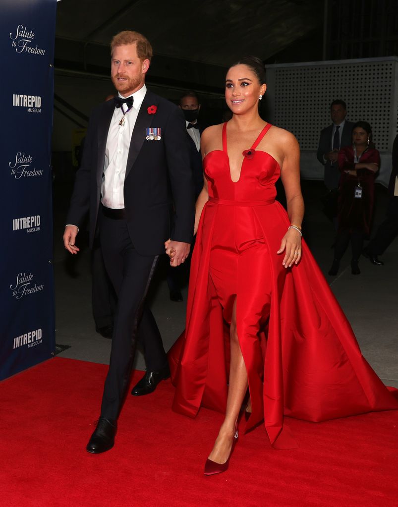 Prince Harry in black tie and Meghan Markle walking in red dress