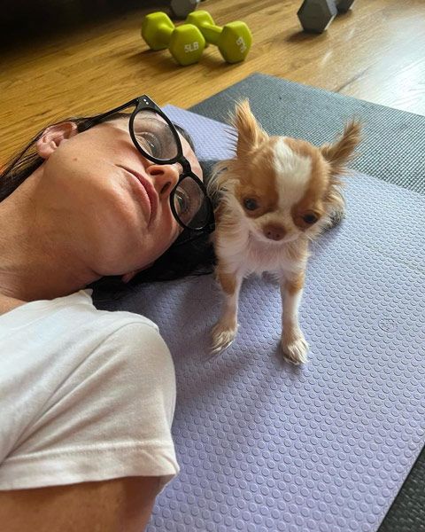 Demi and her dog Pilaf lying on a yoga mat