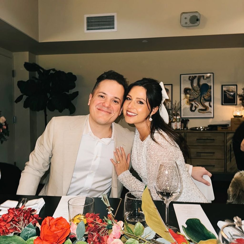 Jeff Arcuri and Katie Thurston pose for a picture across a dinner table 