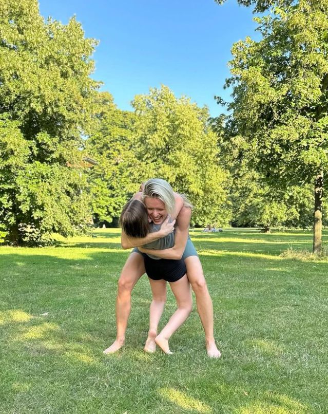 A blonde woman embracing a young girl in a park