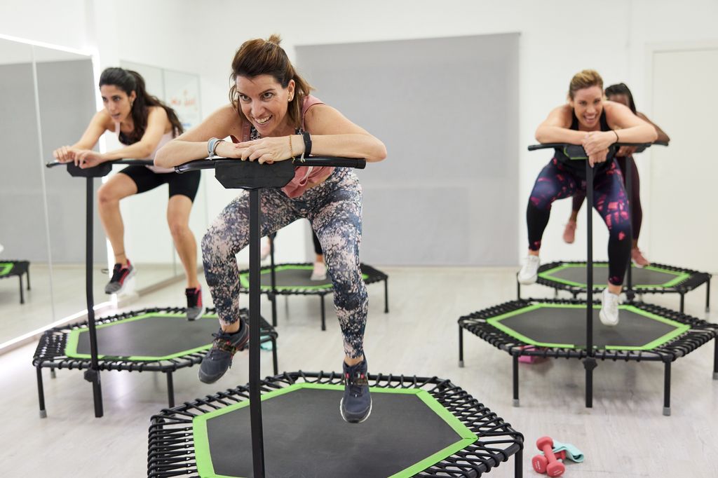 A mid-adult instructor jumping on a Fitness trampoline.
