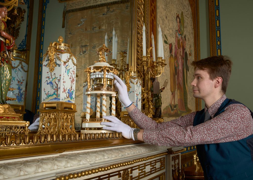 A Horological Conservator adjusts a late-18th-century French marble mantel clock in the Centre Room in the East Wing of Buckingham Palace.