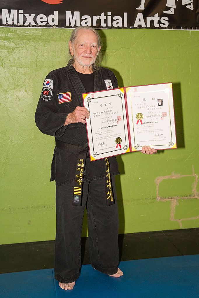 Musician Willie Nelson is presented with his 5th Degree Black Belt in the art of Gong Kwon Yu Sul by Grand Master Sam Um (R) at his studio Master Martial Arts on April 28, 2014 in Austin, Texas.
