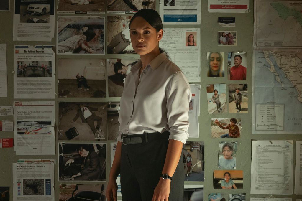 female detective standing in front of wall full of pictures