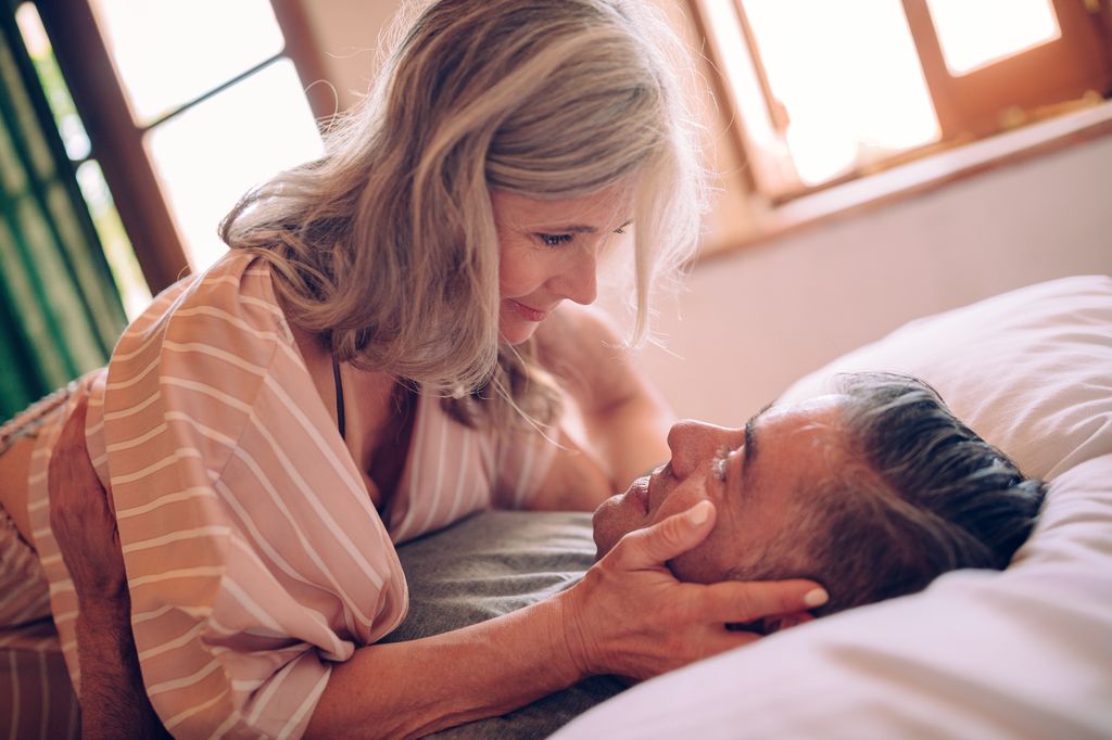 Senior couple flirting and looking in each other's eyes with desire while relaxing in bed