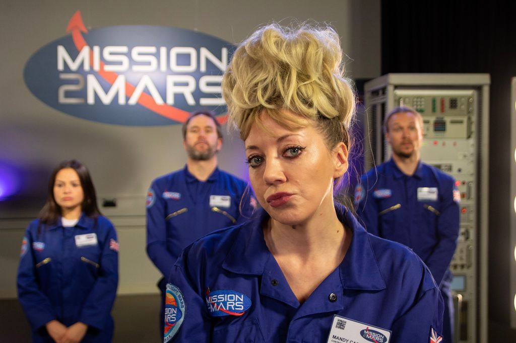 woman in blue jumpsuit standing in front of group of people