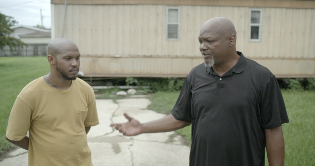 Two Black men talking to each other outside of a mobile home