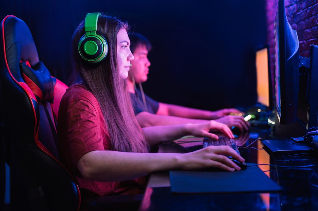 Boy and girl playing computer games together under neon lighting