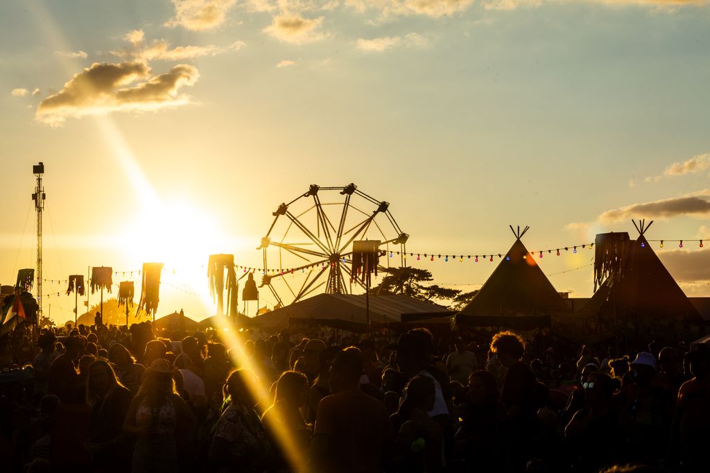 A fairground in the gloaming with people in a crowd in the foreground