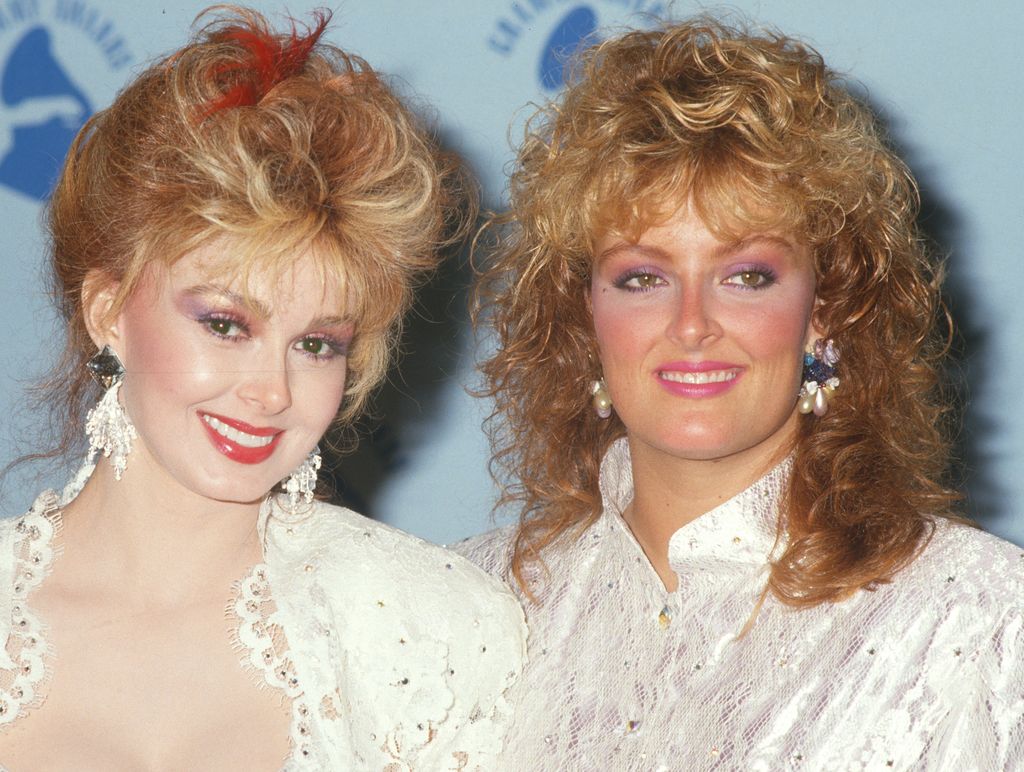 Naomi Judd (1946 - 2022) (left) and her daughter, Wynonna Judd smiling next to each other