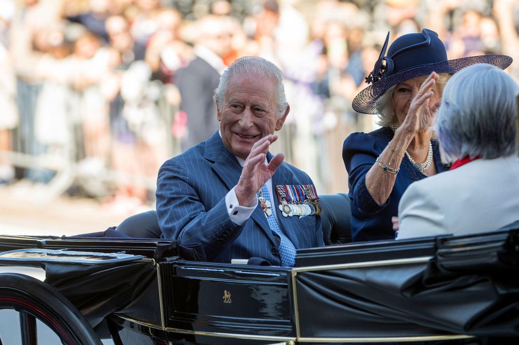 King Charles and Queen Camilla waving from a carriage