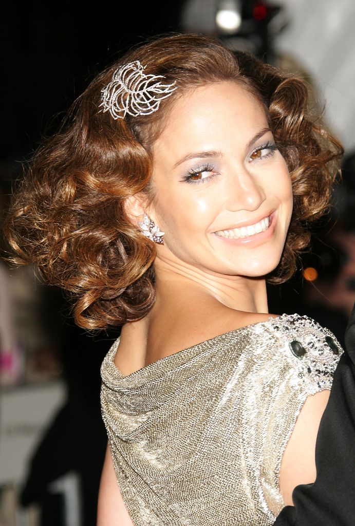 Jennifer Lopez at the 2006 Met Gala with diamond feather hairpiece and earrings, wearing a gold gown.