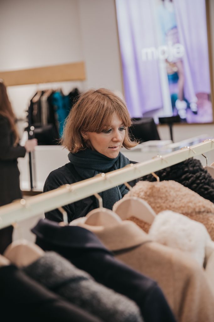 Alexandra browsing a rack of clothes