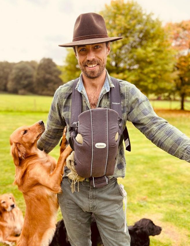 James Middleton with a baby in a baby grow and four dogs