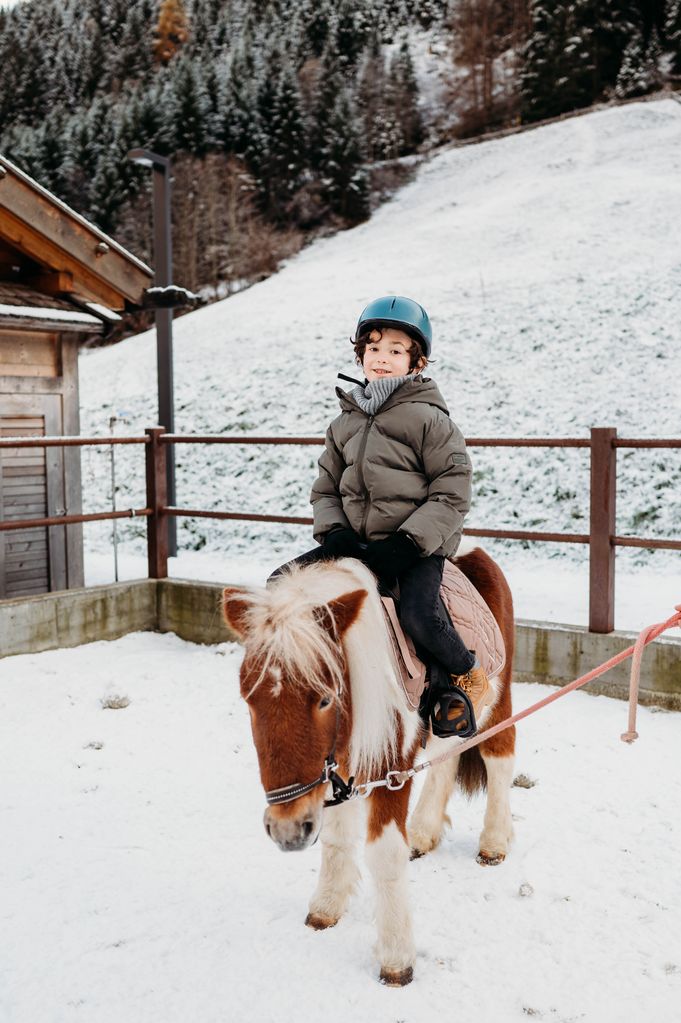 A boy riding a white and brown pony