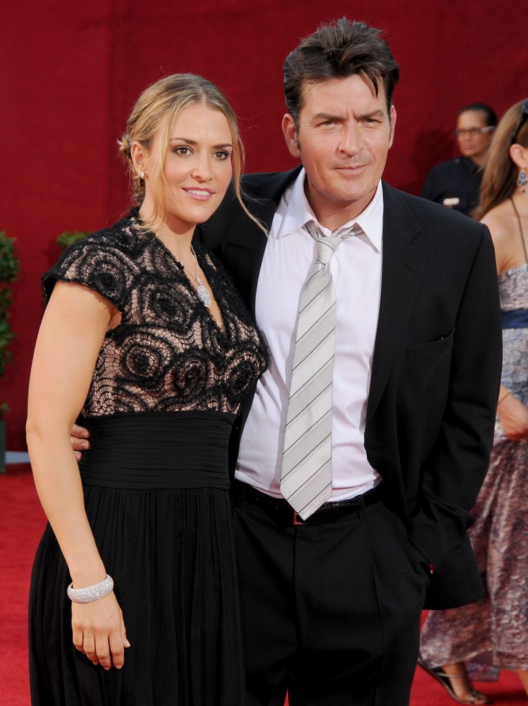Brooke Mueller in black dress and Charlie Sheen in suit on red carpet